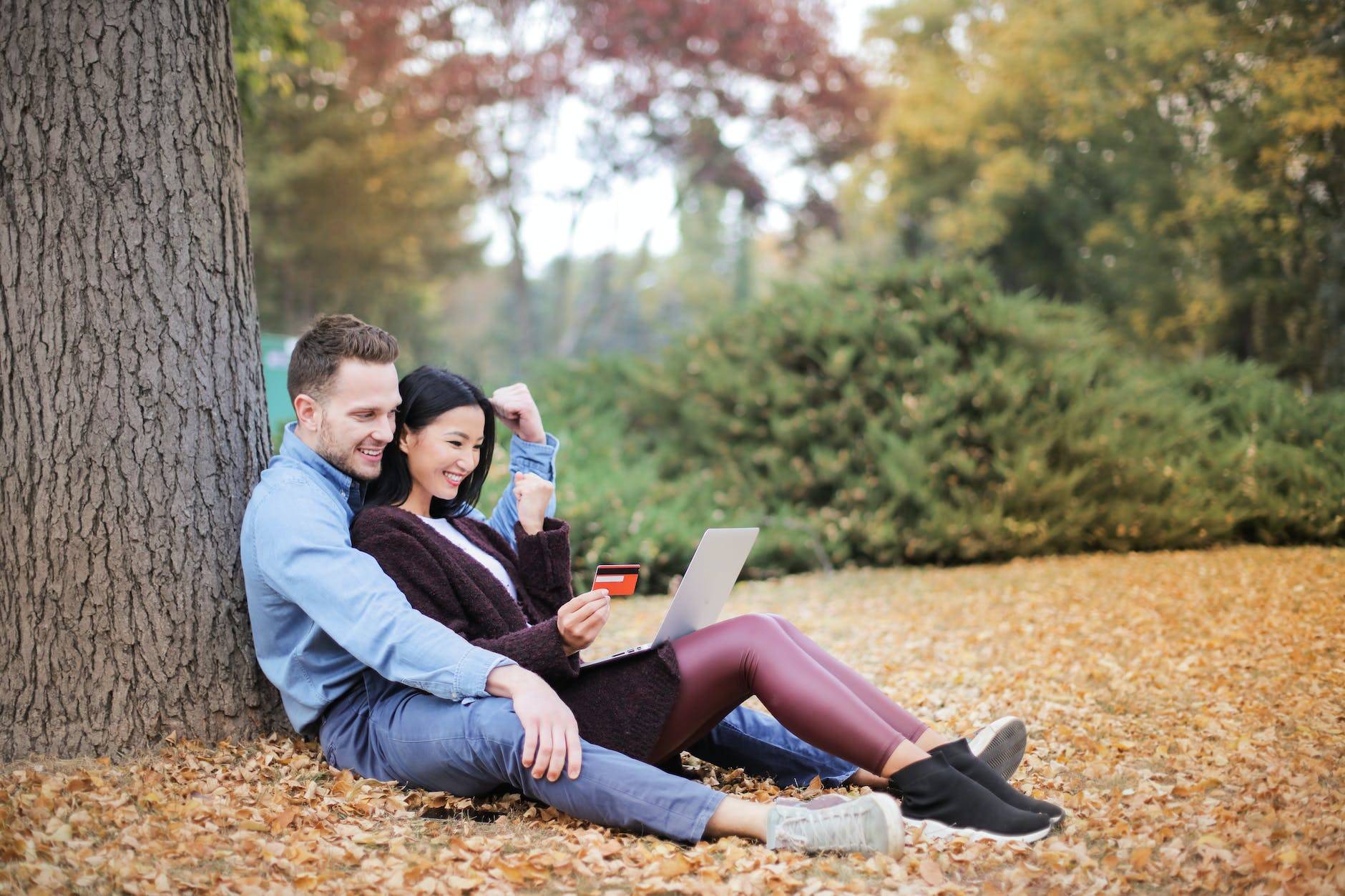 couple reclining beside tree trunks