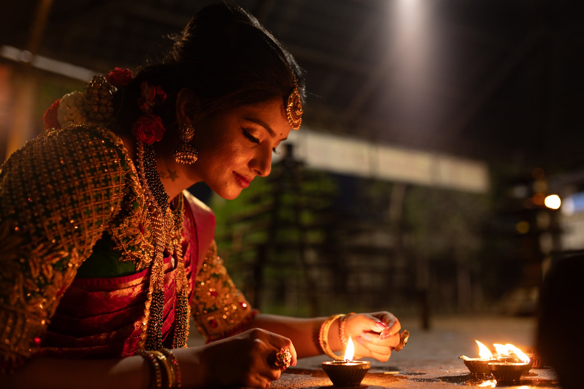 woman in sari lighting candles during diwali